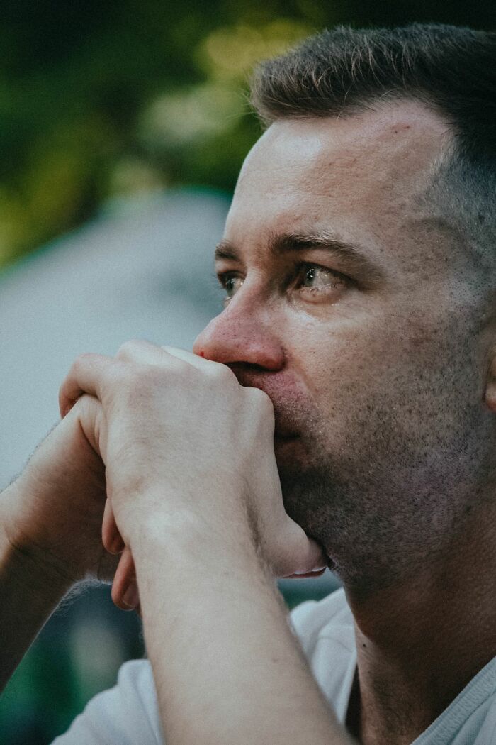 Anxious man with hands clasped to his face, experiencing an urgent feeling of dread