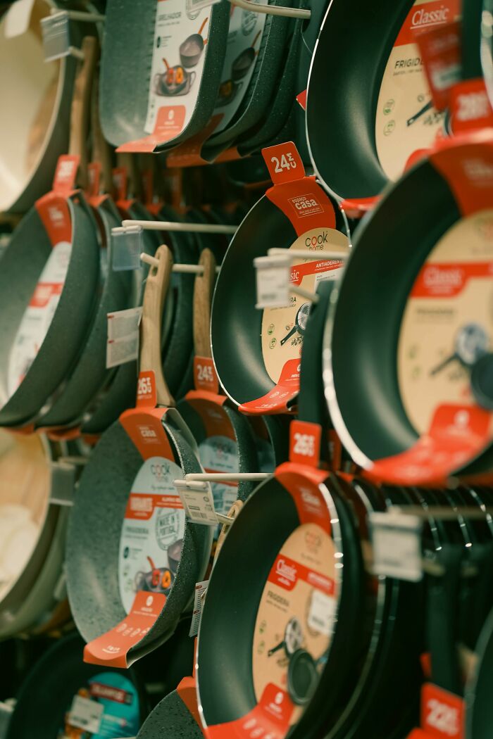 Assorted non-stick frying pans hanging on display shelves, representing companies consumers refuse to support.