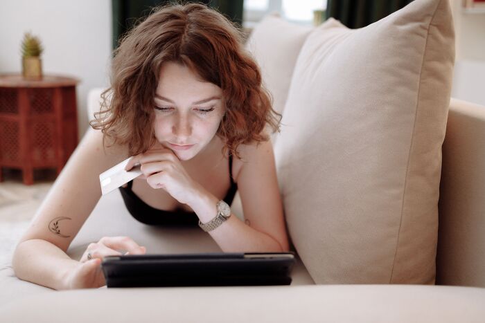 A woman holding a credit card while using a tablet, shopping online behind the scenes at companies people trust.