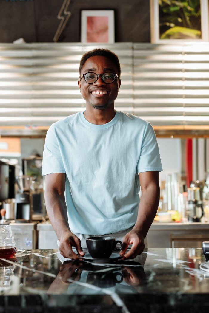 A smiling barista serving a cup of coffee highlighting clever life tricks for daily routines