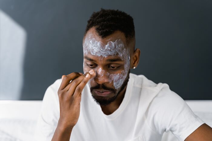 A man applying a skincare face mask, demonstrating actions where professionals lose trust.
