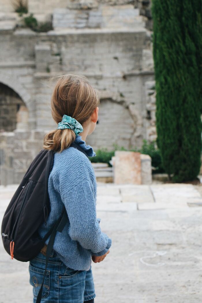 A young child wearing a backpack walking outdoors instead of going trick-or-treating for candy.