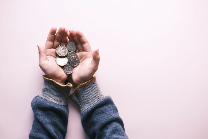 Child holding a handful of coins given instead of candy while trick-or-treating.