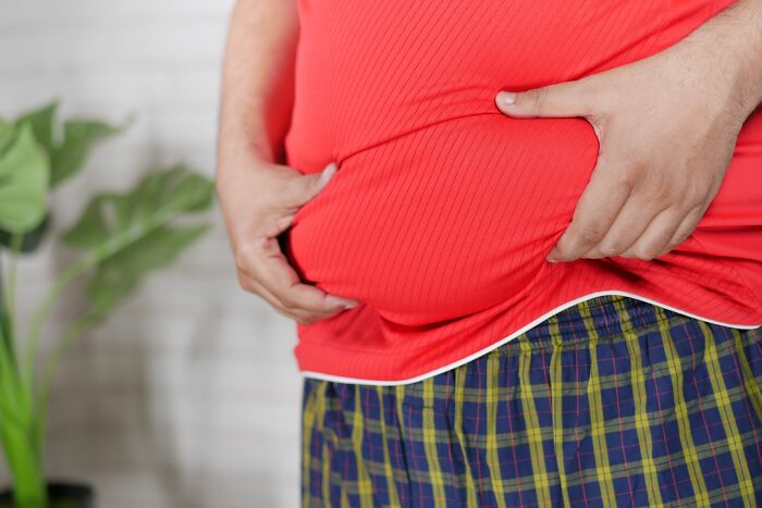 Close-up of a person touching their belly, illustrating physical health discussions with doctors and nurses.