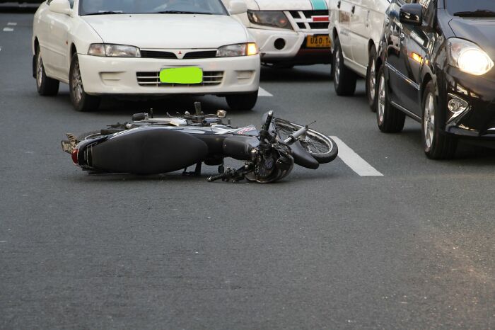 A motorcycle lies on its side in the middle of a road after an accident, evoking an urgent feeling of danger