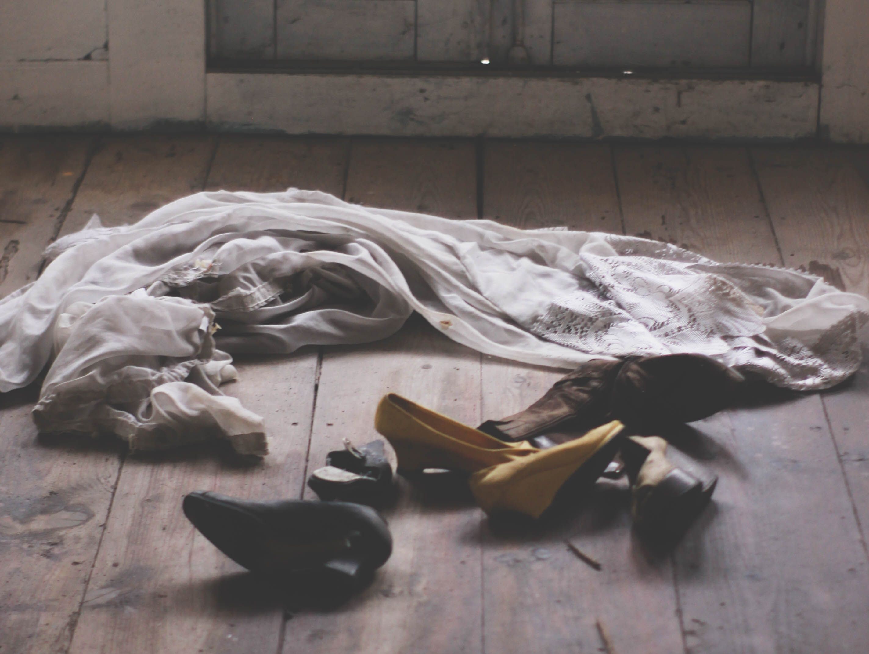 Unfamiliar shoes and messy clothes scattered on a wooden floor Unfamiliar shoes and messy clothes scattered on a wooden floor