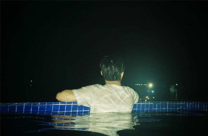 A person leaning on the edge of a pool at night, evoking chilling stories of gut feeling moments.