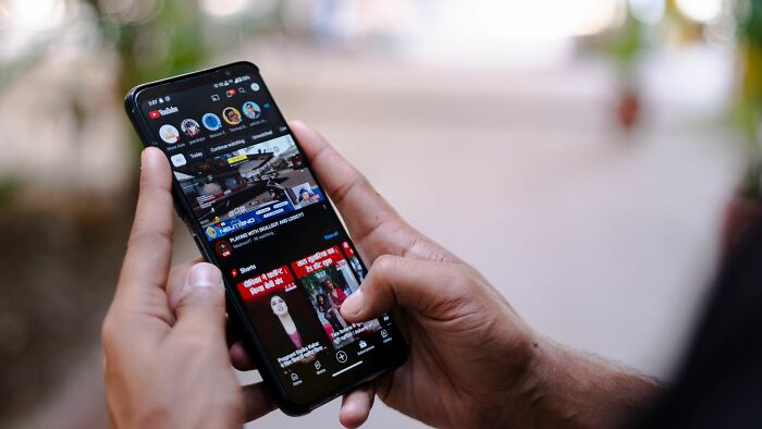 Hands holding a smartphone with social media app, one of the companies people refuse to give another dollar to.