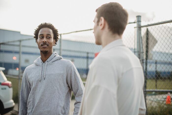 Two men conversing outdoors near a fence, sharing chilling stories of when people trusted their gut feeling.