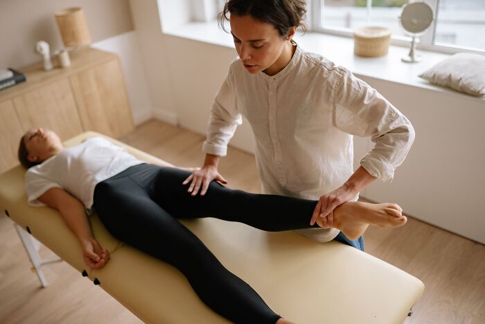 A physical therapist stretching a client leg, showing actions that make clients lose trust.