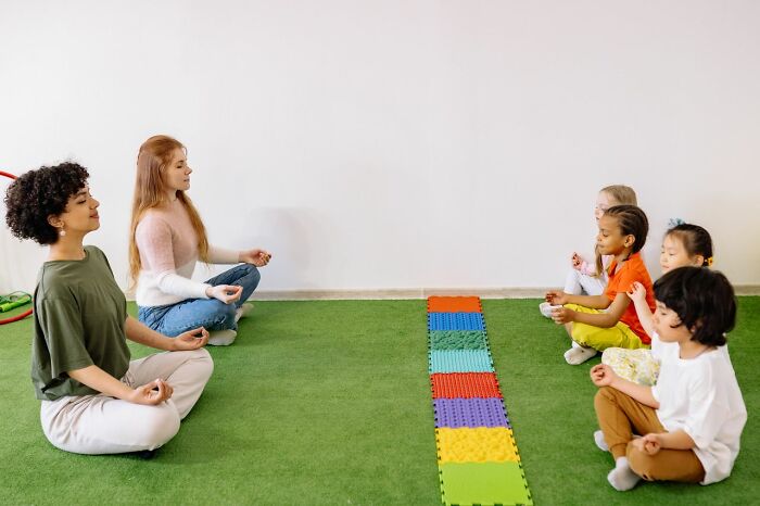 Adults and children practicing meditation on colorful foam mat