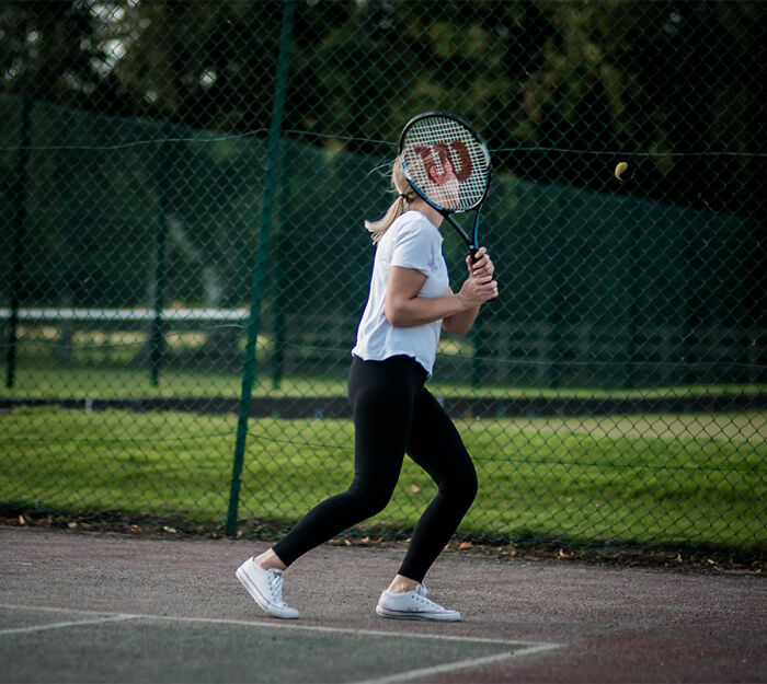 A active teen girl playing tennis outdoors on a court