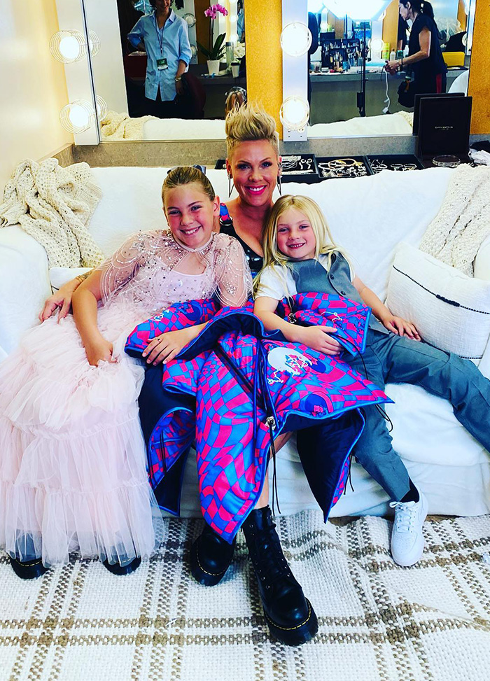 Singer Pink sitting on a sofa with her two smiling children in a backstage dressing room.