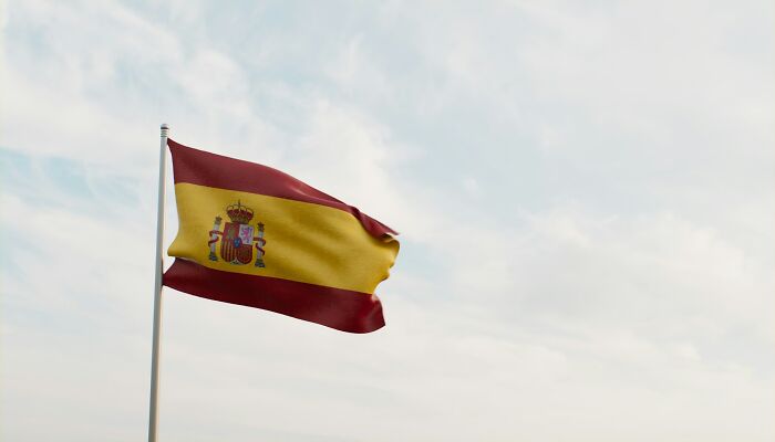 National flag of Spain waving against a cloudy sky in a context of infidelity stories.