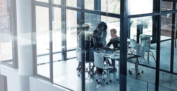 A group of corporate industry insiders meeting in a modern glass office room.