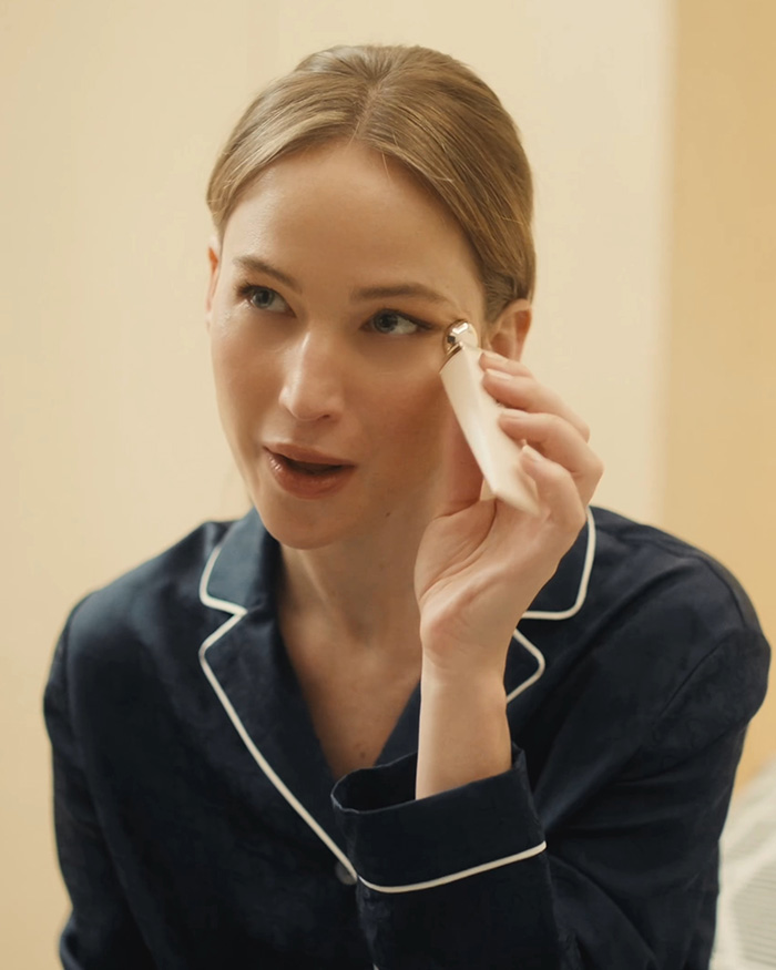 Jennifer Lawrence applying a beauty product to her face amid plastic surgery rumors