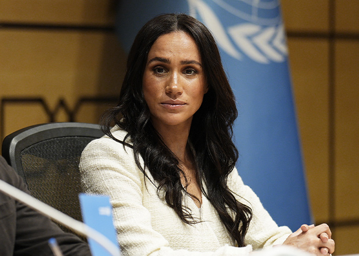 Meghan Markle seated at a formal event listening attentively. Meghan Markle seated at a formal event listening attentively.