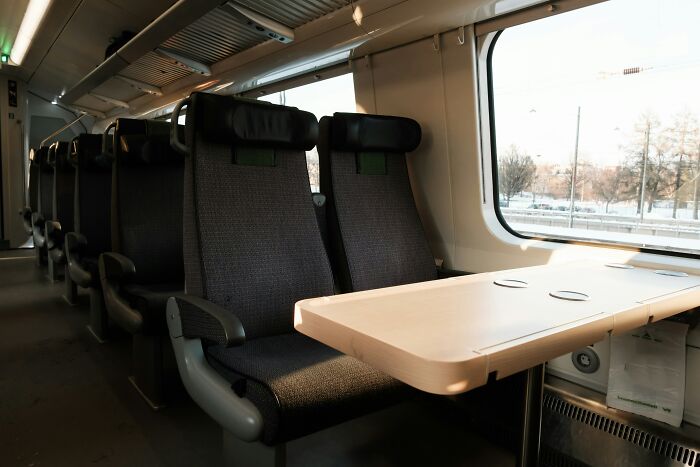 Empty train compartment with seating and a table, showing space for positive masculinity