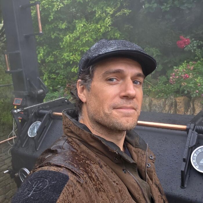 Henry Cavill smiling outdoors, demonstrating positive masculinity and warmth.