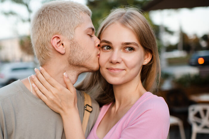 Blonde man kissing his partner on the cheek as an example of positive masculinity and affection.