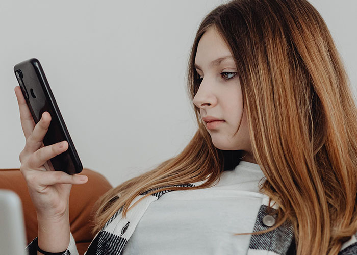 A teenage daughter looks at her smartphone after reading an entitled aunt Halloween invite.