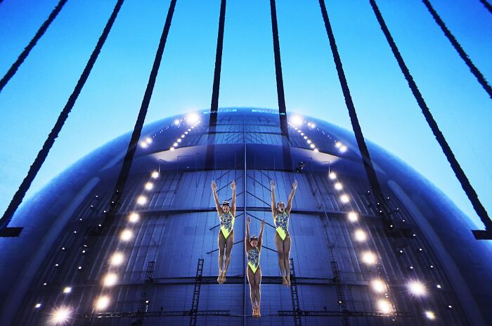 Synchronized aerial gymnasts performing with blue lighting at Siena International Photo Awards