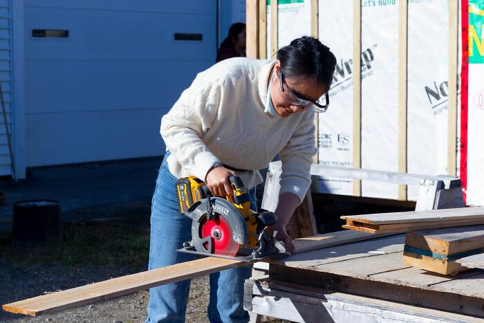 A woman operating a circular saw on a construction site, risking getting fired