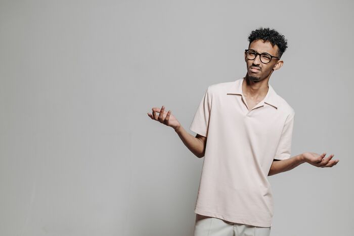 A confused young man shrugging his hands after getting fired.