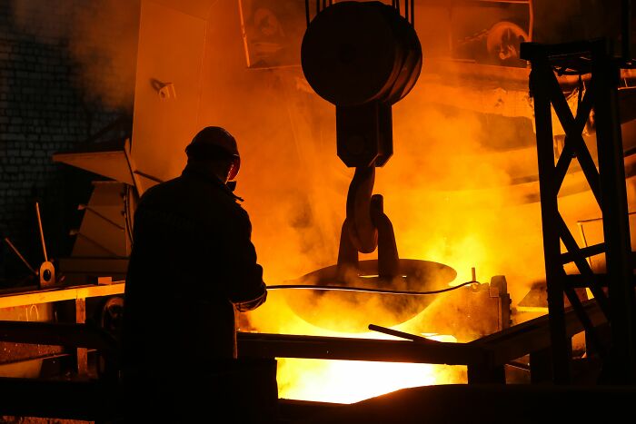 An industrial worker standing near molten metal, tied to stories of workers who got fired quickly.