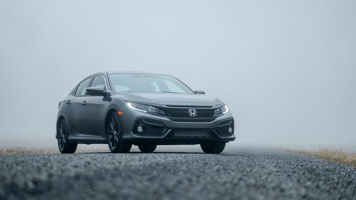 A grey sedan parked on a misty road, symbolic of commuting before someone got fired.