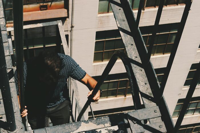 A man walking down a metal fire escape stairs, representing workers who got fired early on.