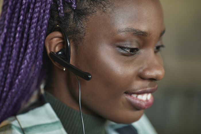 A woman wearing a headset and smiling while working in customer service.
