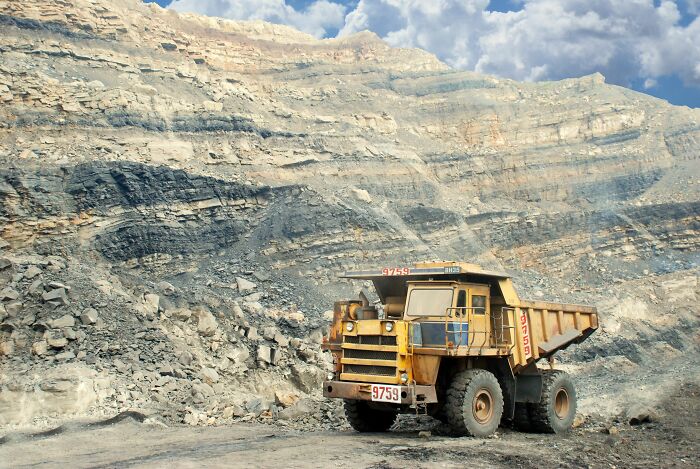 A large yellow dump truck parked at an open-pit quarry or mining site.