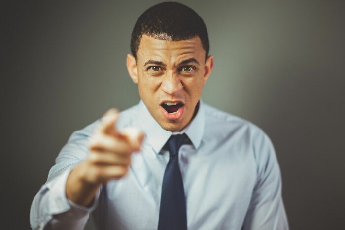 An angry boss shouting and pointing his finger at an employee who got fired