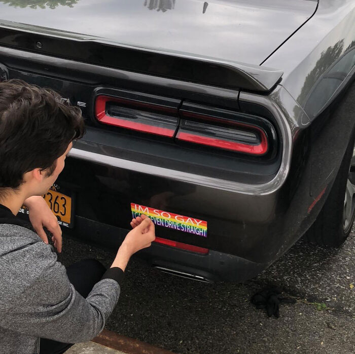 A person sticking a rainbow bumper sticker on a car bumper for a petty revenge story