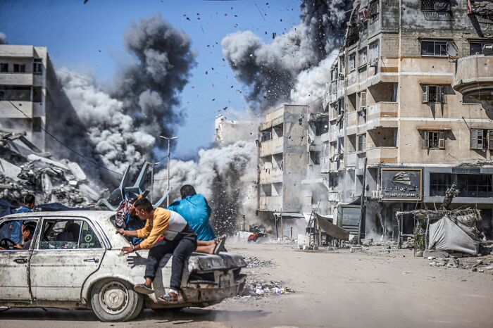 People fleeing explosion with dust and smoke in war-torn city