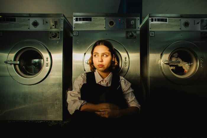 A worried woman looking aside in a laundromat, experiencing an urgent feeling to leave immediately