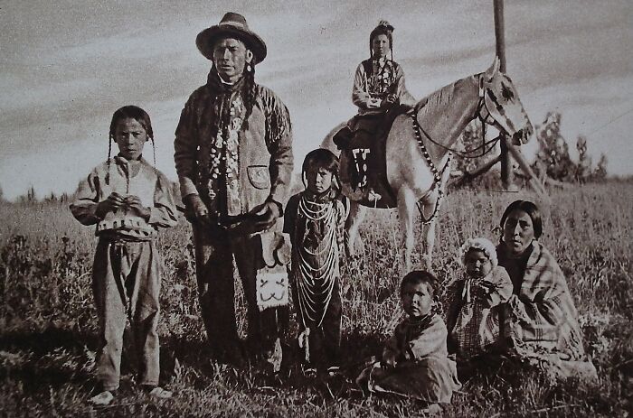 Rare historical photo of Native American family in traditional dress in a field