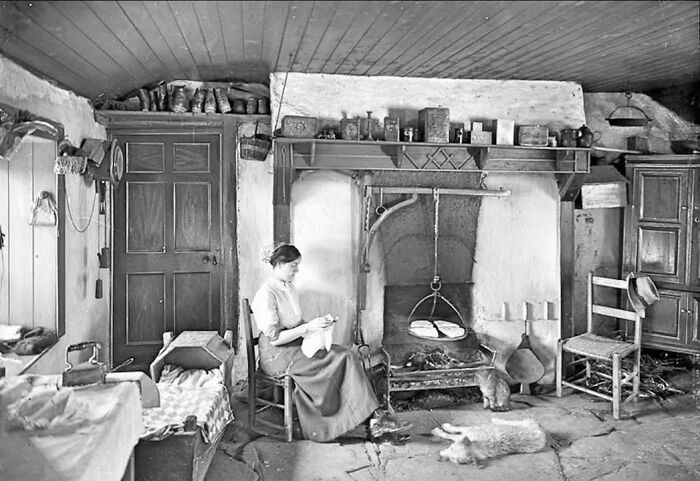 Rare historical photo of woman sitting by hearth in traditional cottage