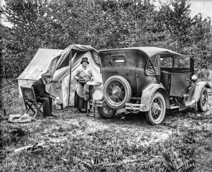 Early 20th century camping site with vintage car and couple