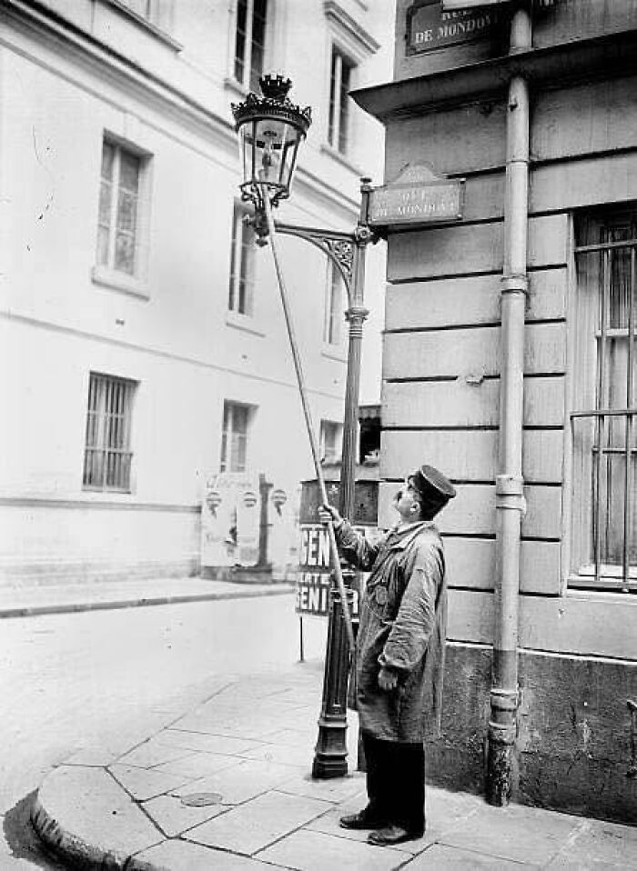 Street lamp lighter using pole in historical city photo