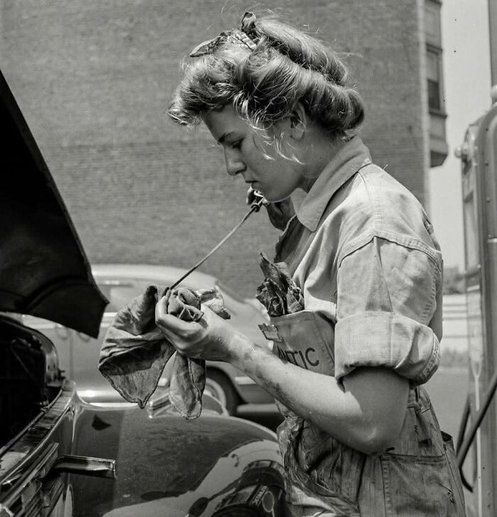 Woman mechanic working on a car engine in vintage historical photo