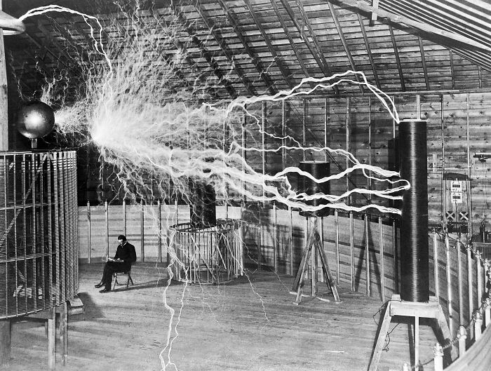 Rare historical photo of Nikola Tesla sitting near electrical arcs in lab