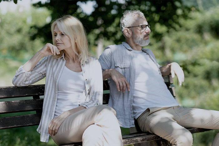 A man suddenly breaks up with girlfriend, sitting distant and upset on a park bench A man suddenly breaks up with girlfriend, sitting distant and upset on a park bench