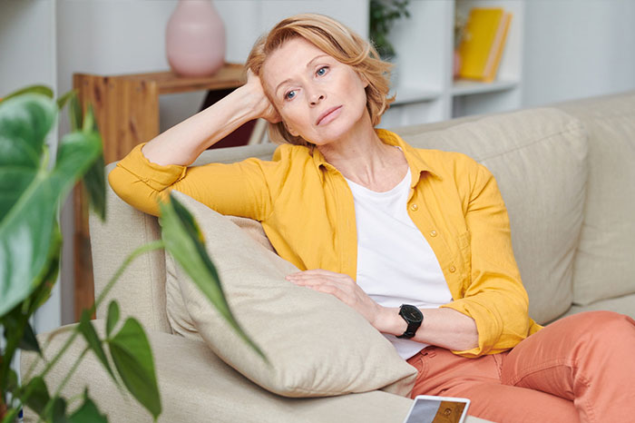 A thoughtful woman sitting on a couch, illustrating a story where a man breaks up with girlfriend A thoughtful woman sitting on a couch, illustrating a story where a man breaks up with girlfriend