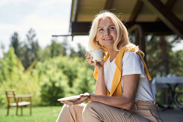 A smiling mature woman enjoying coffee outdoors, finding peace after a man breaks up with girlfriend A smiling mature woman enjoying coffee outdoors, finding peace after a man breaks up with girlfriend