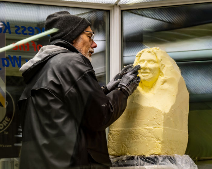 An artist sculpting butter at a state fair event. An artist sculpting butter at a state fair event.