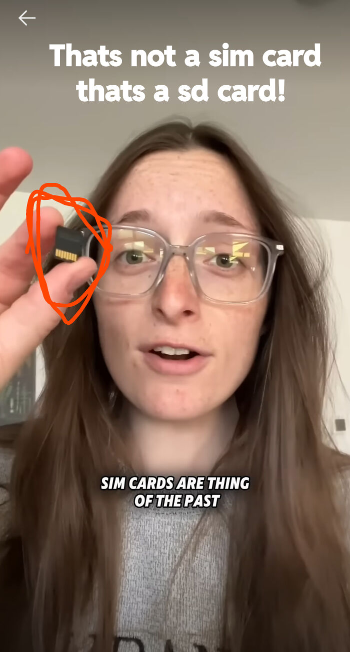 A woman holding an SD card while overlay text mentions SIM cards, showing a funny advertising fail.
