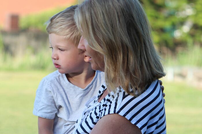 A mother holding her young child outdoors, reflecting the complex emotional impact of family feuds