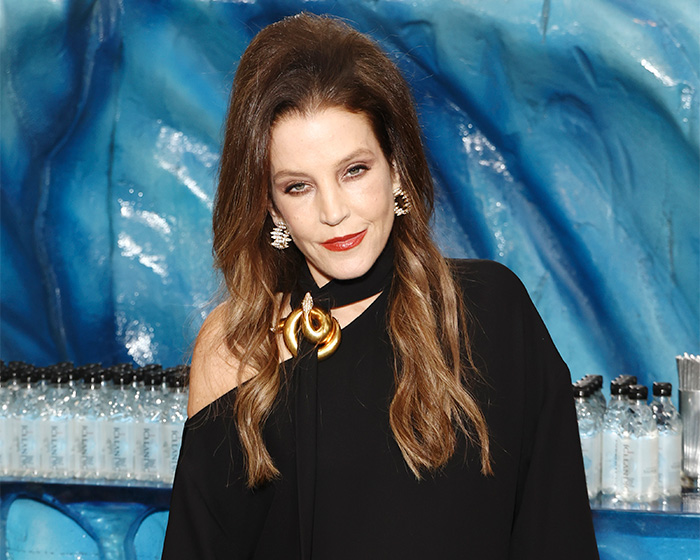 Lisa Marie Presley wearing a black top and gold brooch posing at an event.